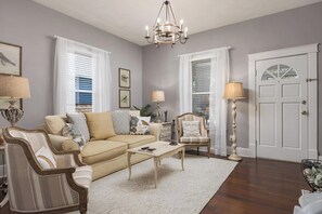 Un salon comprenant un canapé, un fauteuil, une table basse et un lustre.