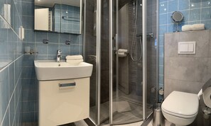 A bathroom with a sink, mirror, shower, and toilet. - Vacation apartment Krampe (Borkum)