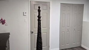 Een slaapkamer met een bed, een ladekast, een deur en een kledingkast.