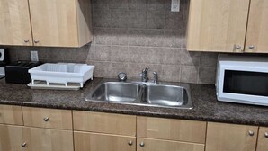 Een keuken met houten kastjes, een dubbele spoelbak, een magnetron en een aanrecht met een afwassysteem.