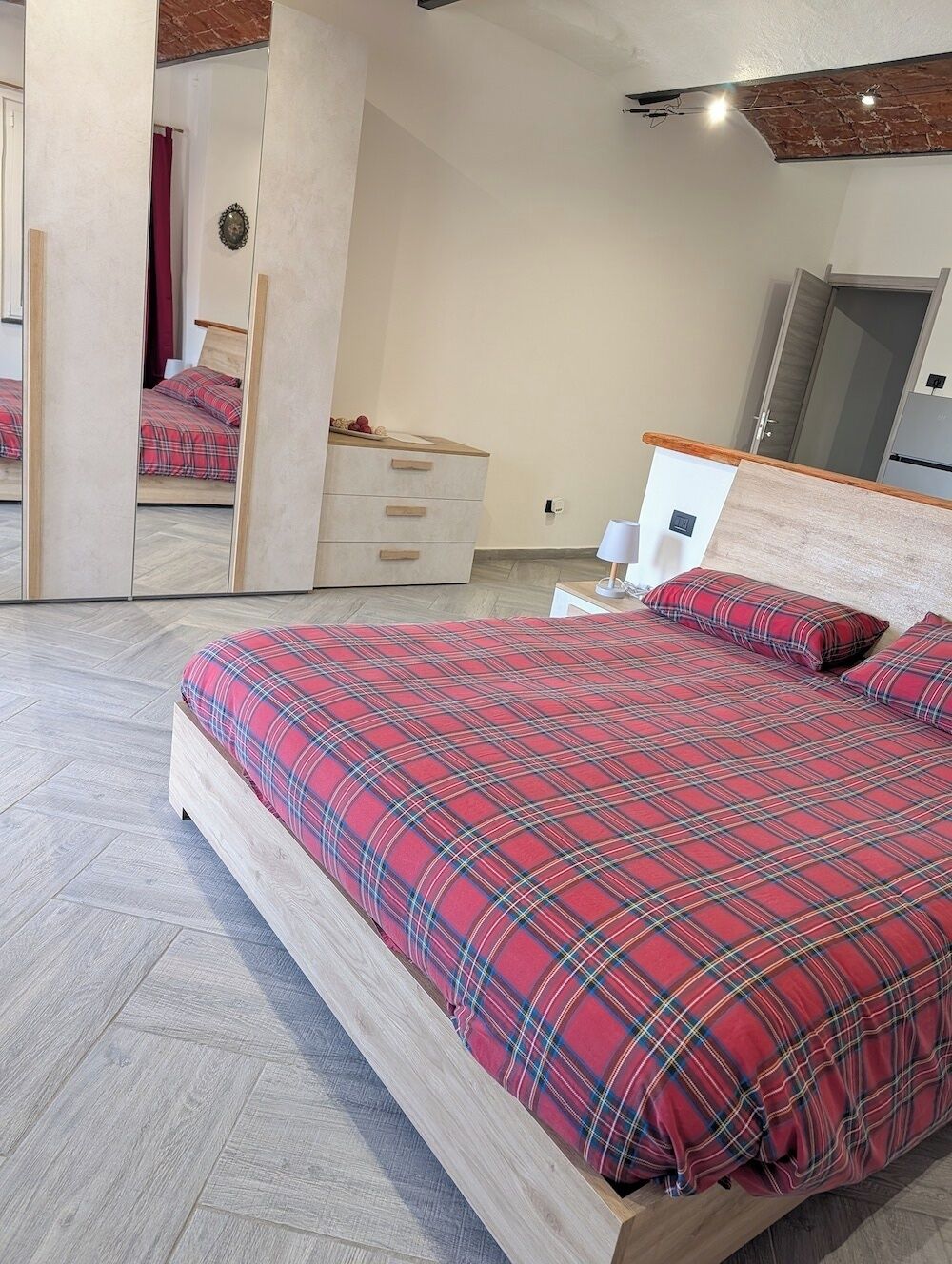 Un dormitorio con cama, cómoda, espejo y armario.