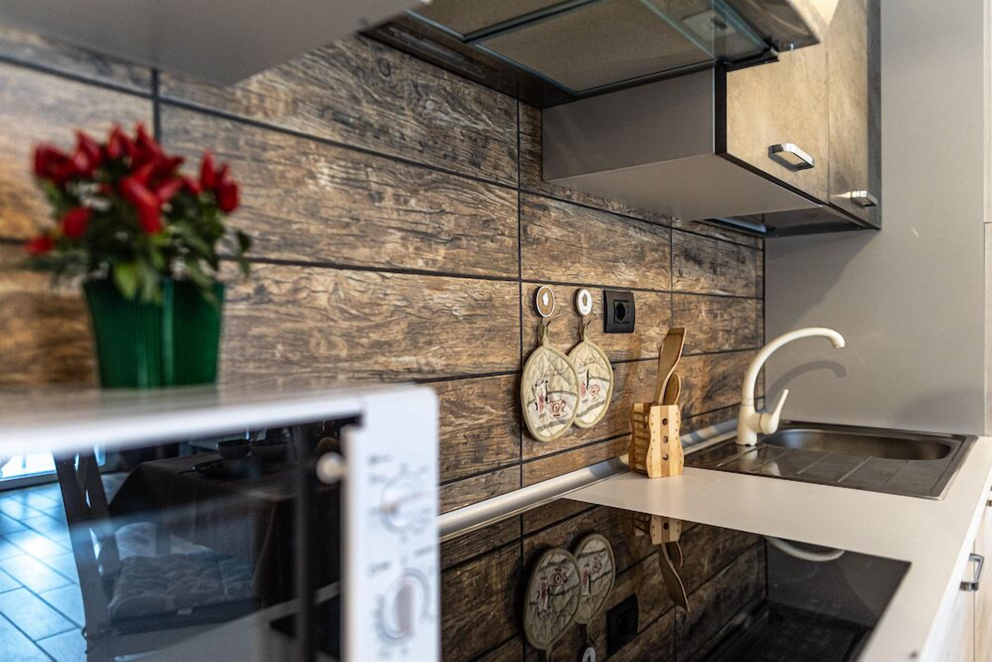 Una cocina con protector de salpicadero de madera, encimera blanca y un lavamanos.