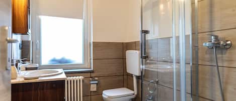 A bathroom with a toilet, bidet, and shower.
