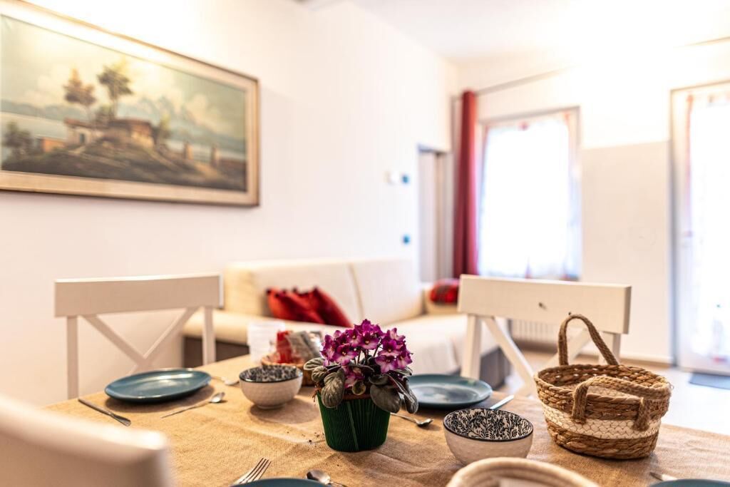 Un comedor con una mesa dispuesta para dos personas, un cuadro en la pared y vistas al exterior.