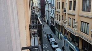 A narrow urban street with buildings on both sides, a clear sky, and a few vehicles. - Hostal Andrea Gran Via (Madrid)