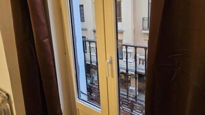 A window with a view of a building with balconies and railings. - Hostal Andrea Gran Via (Madrid)