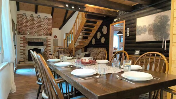 A dining area with a long wooden table set for six, surrounded by wooden chairs. - Entire chalet in Kupjak (Kupjak)
