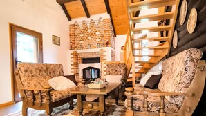 A cozy living room with a brick fireplace, wooden furniture, and a staircase. - Entire chalet in Kupjak (Kupjak)