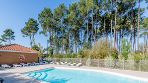 A swimming pool with lounge chairs, a lifebuoy, and a wooden building with a tiled roof. - Large Nature Retreat for 8 by the Lake (Parentis-en-Born)