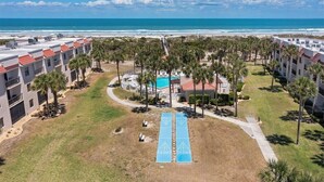 Ett semesterhotell med pool, palmer och utsikt över stranden.