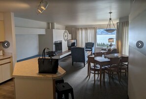 Ein Hotelzimmer mit Küchenzeile, Essbereich, Fernseher, großem Fenster mit Aussicht und Pendelleuchte.
