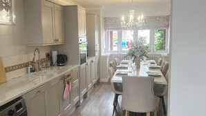 A kitchen with a dining area, a chandelier, and a view of the outside. - Tranquil Solihull Retreat - 3 Bedroom House (Solihull)