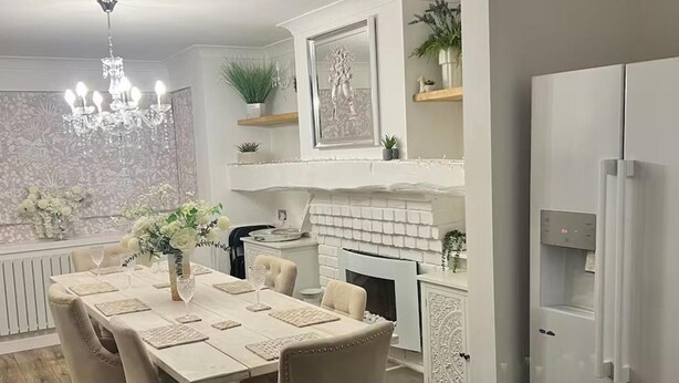 A dining area with a chandelier, a fireplace, and a refrigerator. - Tranquil Solihull Retreat - 3 Bedroom House (Solihull)