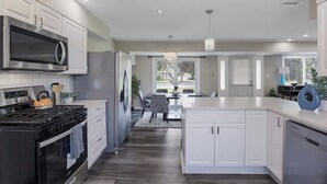 A modern kitchen with white cabinetry, a built-in stove, and a large island. - Spacious 5 Bed 2 bath House (Melrose Park)