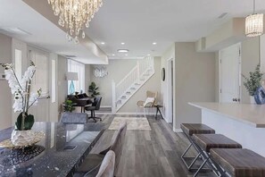 A modern kitchen with a marble countertop, a dining area with a table and chairs, and a staircase leading to another level. - Spacious 5 Bed 2 bath House (Melrose Park)