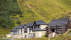 A multi-story hotel with a stone facade, balconies, and a view of a green hillside. - Functional Studio, Heart of the High Pyrenees (Garin)