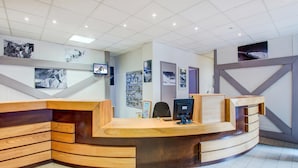 A reception desk with a curved design, a flat-screen TV, and a wall-mounted photo display. - Functional Studio, Heart of the High Pyrenees (Garin)