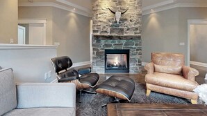 A living room with a stone fireplace, leather chairs, and a sofa.