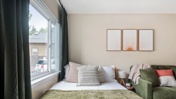 A hotel room with a bed, a green armchair, a window with curtains, and three wall-mounted artworks. - Sunny Mt. Tabor Studio, Full Kitchen, Walk to Parks (Portland)