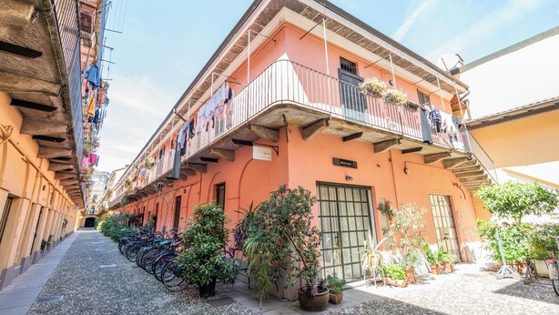 Un bâtiment doté d’un balcon, d’une porte et de plantes en pot.