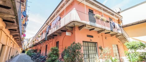 Un edificio con balcón, puerta y plantas en macetas.
