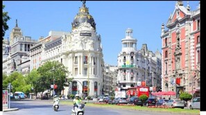 A street with historic buildings, a prominent white building with a dome, and a red bus.