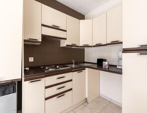 A compact kitchen with a gas stove, a coffee maker, and a toaster on the countertop. - 2 BR Coastal Villa in Solenzara (Sari-Solenzara)