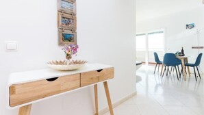 A modern room with a white desk, a vase of flowers, and a dining area with blue chairs. - Tatiana Apartment - Located in one of the most prestigious areas of Portimão. (Portimão)