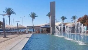 A clear pool with a fountain, palm trees, and a building in the background. - Tatiana Apartment - Located in one of the most prestigious areas of Portimão. (Portimão)