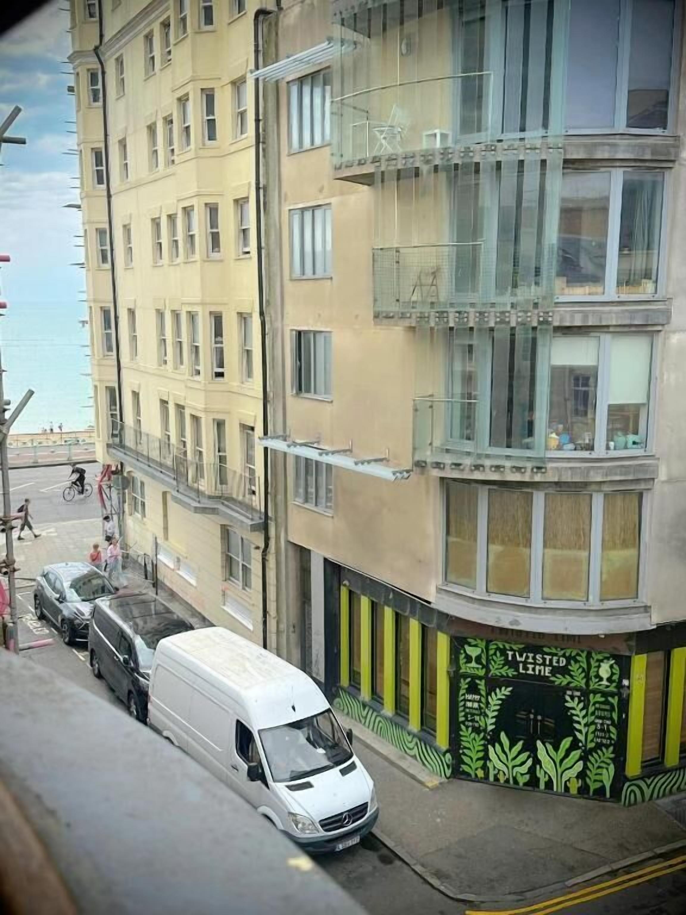 Un immeuble à plusieurs étages devant lequel est garé un fourgon blanc.