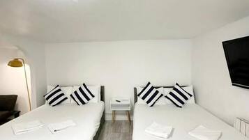 Une chambre d’hôtel avec deux lits, une petite table de chevet, une lampe et un téléviseur.