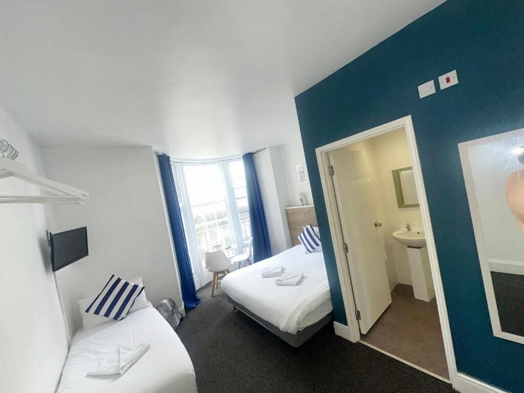 A hotel room with two beds, a bathroom, and a view of the outside.