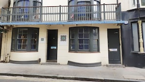 A building with a balcony, numbered doors, and a sign indicating '75 VINTAGE.' - Number 75 (Brighton)