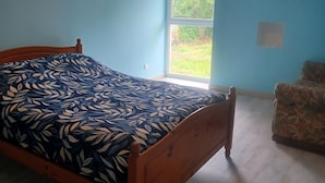 A bedroom with a bed, a window, an air conditioning unit, and a chair. - "At grandpa's" (Limalonges)