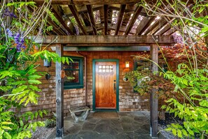A rustic wooden building with a wooden door, stone steps, and a wooden pergola with vines. - Horizon House | Hot Tub, Views, Gardens + Golf (Sebastopol)