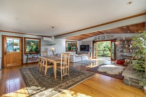 A spacious living area with a wooden dining table, a sofa, and a television. - Horizon House | Hot Tub, Views, Gardens + Golf (Sebastopol)