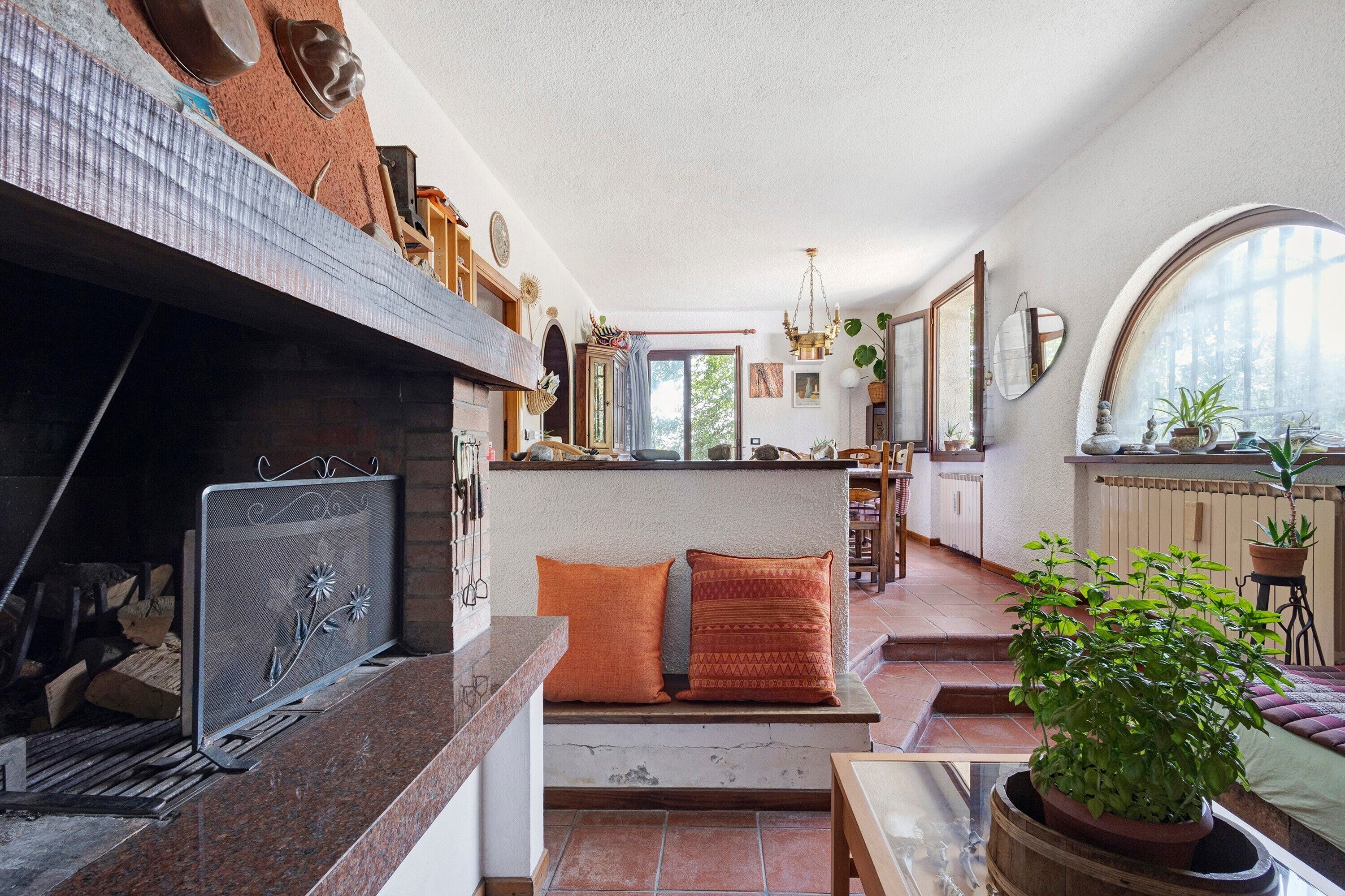 Un amplio espacio de estar con chimenea, asientos y vistas al exterior.