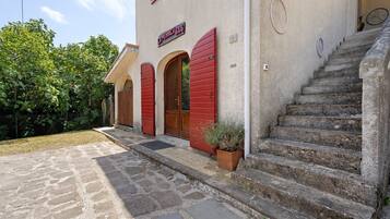 Un edificio con ingresso in pietra, persiane rosse e un cartello con la scritta 'LA PENNICA B&B'.