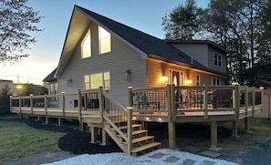 Ein zweistöckiges Haus mit Terrasse, Treppe und überdachter Sitzgruppe.