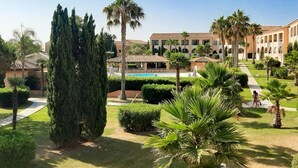 A courtyard with a pool, palm trees, and a building with arches. - Spacious Family Stay Near the Beach (Linguizzetta)
