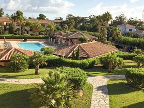 A resort with a swimming pool, palm trees, and a paved walkway. - Spacious Family Stay Near the Beach (Linguizzetta)
