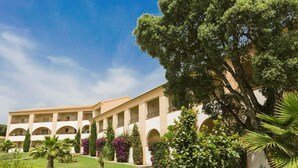 A hotel with a courtyard, multiple balconies, and lush greenery. - Spacious Family Stay Near the Beach (Linguizzetta)