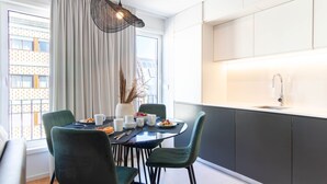 Et moderne køkken med spiseplads, med et stort vindue, et hængende lysarmatur og en indbygget vask.