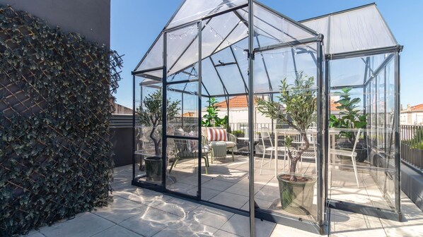 A greenhouse structure with transparent walls, a tiled patio, and potted plants inside. - Rooftop Glasshouse Retreat by LovelyStay (Porto)