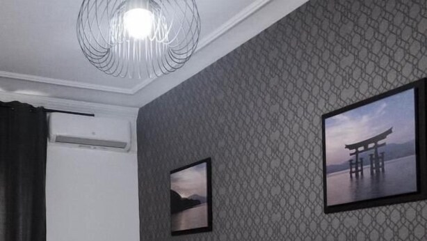 A hotel room with a large bed, two smaller beds, a ceiling light fixture, a wall-mounted air conditioner, and two framed pictures. - Hostal Andrea (Madrid)