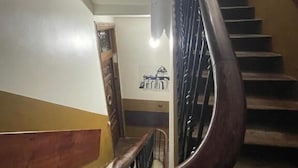 A staircase with a wooden handrail and metal balusters, leading to a landing with a wall-mounted picture. - Hostal Andrea (Madrid)