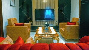 A modern living room with a flat-screen TV, two armchairs, a coffee table, and red sofas. - Wealth's Khort Apartment (Keffi)
