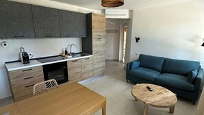 Una cocina moderna con armarios grises, una mesa de comedor con sillas, un sofá azul y una mesa redonda de centro.