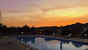 Una piscina con sillones de descanso y vistas a la puesta de sol.