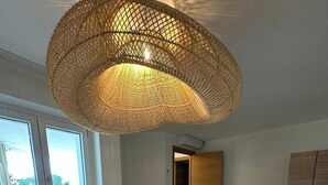 Un dormitorio con una cama grande, una lámpara de techo tejida, un armario de madera y un banco.